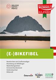 Ein majestätischer Bergspitz spiegelt sich in einem ruhigen See wider. Im Vordergrund ist der Titel "(E-)BIKEFIBEL" in auffälliger Schrift zu sehen.