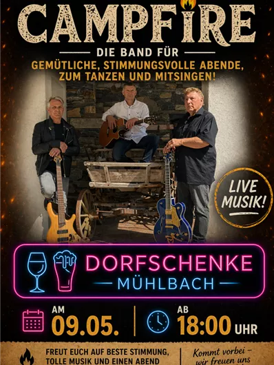 Drei Musiker stehen in einer rustikalen Umgebung mit Akustikgitarren. Sie lächeln und haben Spaß, während im Hintergrund eine Feuerstelle zu sehen ist.