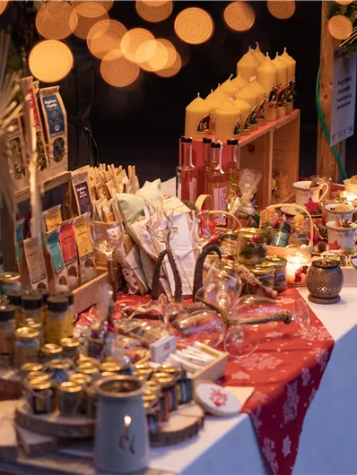 Een feestelijk versierde stand met verschillende lekkernijen en cadeaus. Warm licht en een feestelijke sfeer creëren een uitnodigende ambiance.