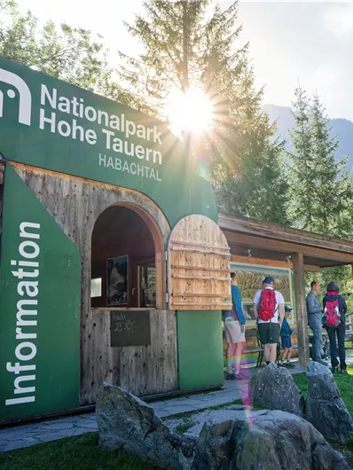 Ein Informationszentrum im Nationalpark Hohe Tauern. Besucher stehen vor dem Gebäude und genießen die Natur.