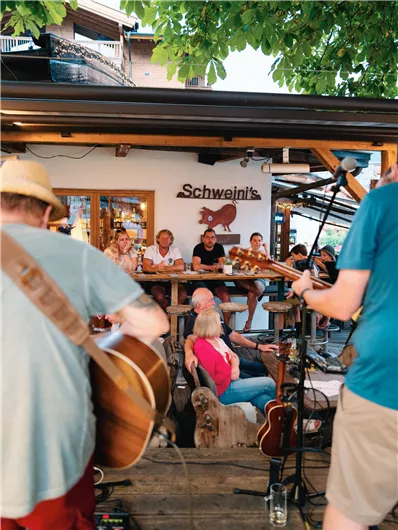 Een gezellig restaurant met livemuziek. Gasten zitten ontspannen aan een houten barricade en genieten van de sfeer.