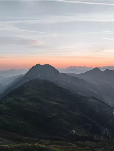 Eine beeindruckende Berglandschaft während des Sonnenuntergangs. Die sanften Hügel sind von sanften Nebelschwaden umhüllt.