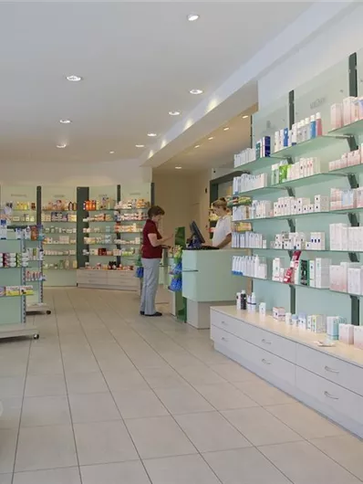 Ein moderner Verkaufsraum mit Regalen voller Kosmetik- und Pflegeprodukte. Kunden stehen an der Theke und beraten sich.