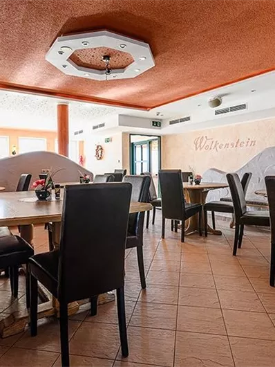 A cozy restaurant with a warm color tone and stylish seating. The tables are set for guests, and the atmosphere is inviting.