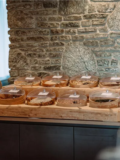 A stylish buffet with various treats in transparent containers. In the background, you can see a stone wall and plants.