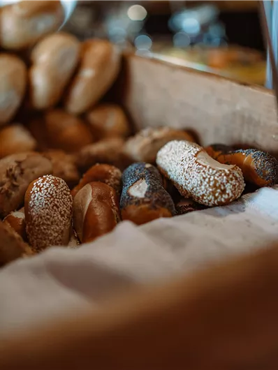 A basket with various rolls and pastries. The fresh baked goods are resting on a white cloth.