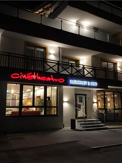 Ein modernes Gebäude mit einem Restaurant. Die Fassade ist beleuchtet und zeigt den Namen des Lokals.