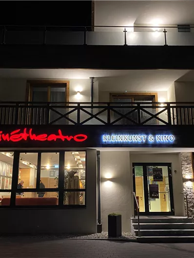 Ein modernes Restaurant mit beleuchtetem Schild. Die Fassade hat große Fenster und eine einladende Atmosphäre.