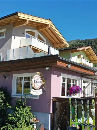 A charming building in the mountains, surrounded by plants and flowers. The architecture is modern and inviting.