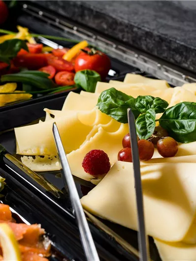 Een buffet met verschillende kazen en verse groenten. Kleurige tomaten, paprika's en radijsjes completeren de keuze.