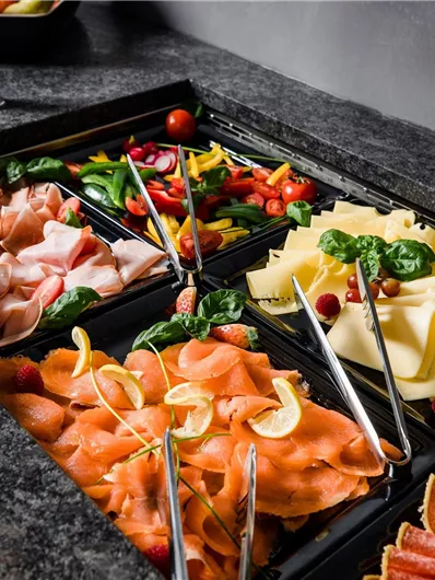 Een heerlijk buffet met verschillende soorten vlees en kaas, verse groenten en fruit. De aantrekkelijke presentatie nodigt uit tot genieten.