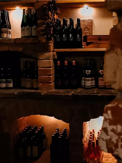 A cozy wine cellar with shelves full of bottles. Soft light illuminates the walls and the wine storage.