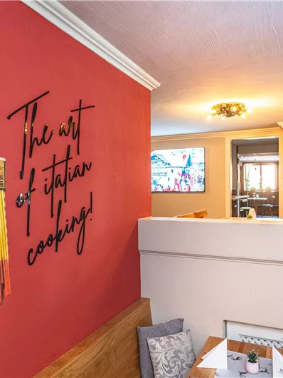 A cozy restaurant with a wall design featuring a paintbrush and the inscription "The art of Italian cooking!" The colors of the paintbrush evoke the Italian flag.