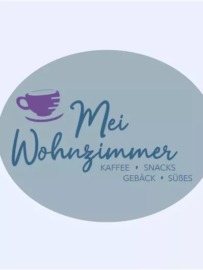 Ein ovales Logo mit dem Schriftzug “Mein Wohnzimmer”. Darunter stehen die Wörter “Kaffee, Snacks, Gebäck, Süßes”.