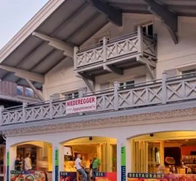 Een modern restaurantgebouw met een uitnodigende buitenruimte. De gevel toont kleurrijke reclameposters voor eten en drinken.