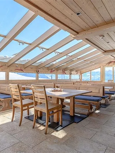 A bright, inviting room with wooden furniture and large windows. The view of the mountains creates a pleasant atmosphere.