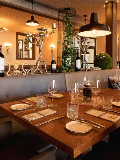 An elegant restaurant with a stylish decor. The table is set for a fine dinner and plants create a pleasant atmosphere.