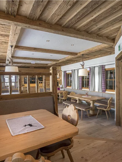 Een gezellig restaurant met warme houten details en helder licht. De tafels zijn netjes gedekt en er zijn comfortabele zitmogelijkheden.