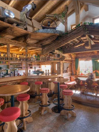 Een rustieke bar met houten decor en gezellige zitplaatsen. De ruimte is helder verlicht en nodigt uit om te blijven hangen.