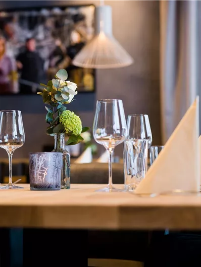 Een stijlvol gedekte tafel in een modern restaurant. Glazen, bestek en een bloemdecoratie geven de ambiance elegantie.