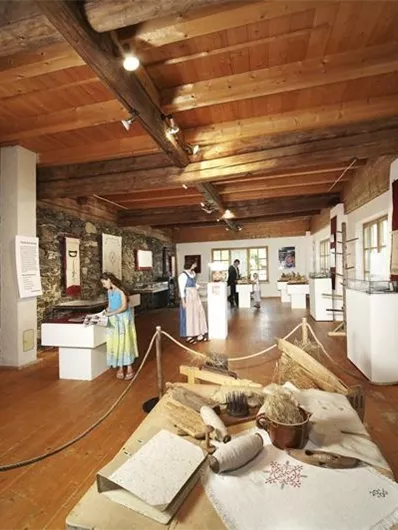 Ein Museum mit Holzdecke und Ausstellungsstücken. Im Hintergrund sind Bücherregale und Besucher zu sehen.