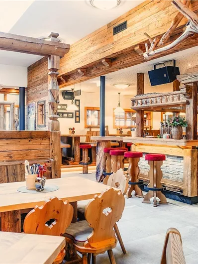 Ein gemütliches Restaurant mit Holzmöbeln und warmem Ambiente. Die Einrichtung ist rustikal und einladend.