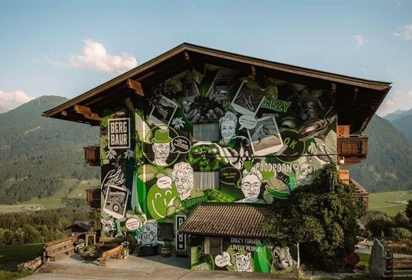 Ein bunt gestaltetes Haus mit künstlerischen Wandmalereien. Die Zeichnungen zeigen verschiedene Charaktere und Texte in lebhaften Farben.