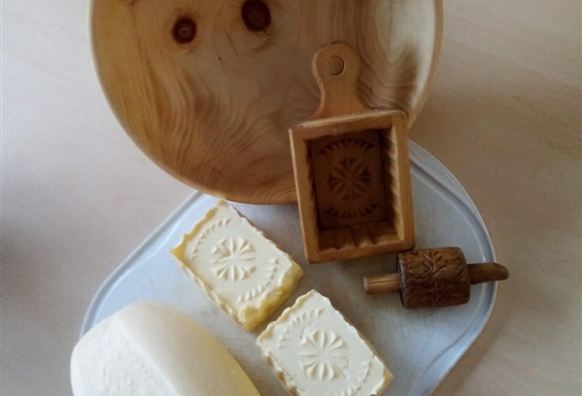 Ein Holzschalen mit verschiedenen Formen von Käse und einem Holzstempel. Die Käse sind dekorativ und handgefertigt.