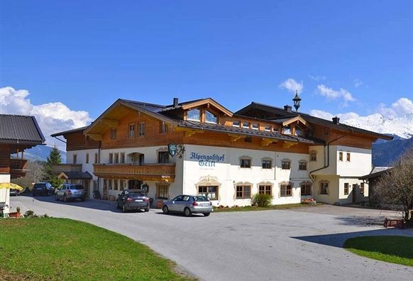 Ein rustikales Gebäude im alpinen Stil mit mehreren Etagen und einem schönen Außenbereich. Das Hotel befindet sich in einer malerischen Umgebung mit klar blauem Himmel.