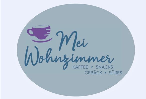 Ein ovales Logo mit dem Schriftzug “Mein Wohnzimmer”. Darunter stehen die Wörter “Kaffee, Snacks, Gebäck, Süßes”.