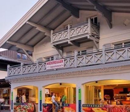 Ein modernes Restaurantgebäude mit einem einladenden Außenbereich. Die Fassade zeigt bunte Werbeplakate für Speisen und Getränke.