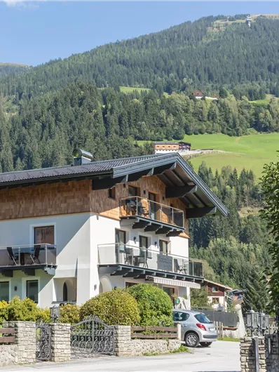Een modern huis in de bergen met balkons en een mooie tuin. De omgeving is groen en schilderachtig.