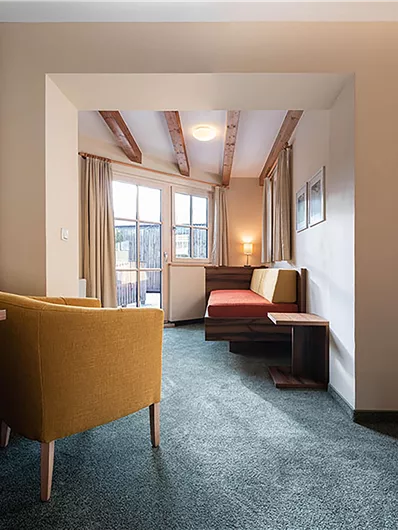Ein helles und modernes Zimmer mit zwei bequemen Stühlen und einer gemütlichen Sitzecke. Große Fenster sorgen für viel Tageslicht.
