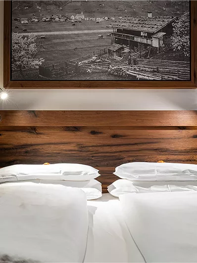 Ein gemütliches Schlafzimmer mit einem großen, bequemen Bett und einem Holzbrett. Über dem Bett hängt ein Bild einer Landschaft.