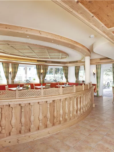 Ein einladendes Restaurant mit Holzverkleidung und roten Sitzbänken. Große Fenster sorgen für viel Licht und einen Blick auf die Umgebung.