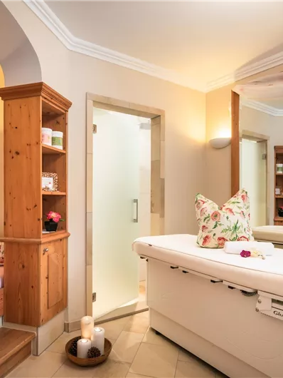 Ein eleganter Wellnessraum mit Holzregalen und einem gemütlichen Ruhebereich. Das Licht und die Dekoration schaffen eine entspannende Atmosphäre.