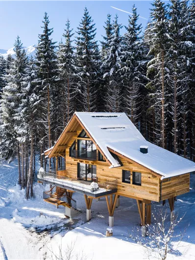 Een modern houten huis te midden van met sneeuw bedekte bomen. Het landschap oogt rustig en winters.