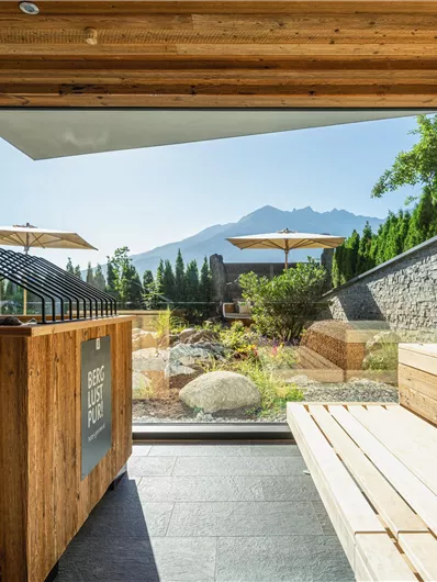 Een moderne wellnessruimte met houten panelen en uitzicht op de bergen. De grote ramen laten veel daglicht binnenvallen en creëren een ontspannende sfeer.