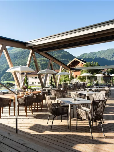 Eine moderne Terrasse mit schönen Blick auf die Berge. Tische und Stühle laden zum Entspannen im Freien ein.