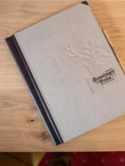 Ein elegantes notizbuch auf einem Holztisch. Es hat eine graue Hülle und ein eingestempeltes Design.