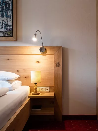 Ein gemütliches Schlafzimmer mit einem bequemen Bett und sanfter Beleuchtung. Die Wände sind warm gehalten, und das Holzdesign verleiht eine natürliche Atmosphäre.