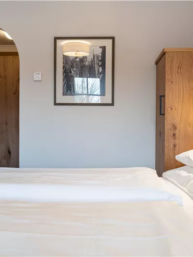Ein gemütliches Schlafzimmer mit einem großen Bett und Holzinterieur. An der Wand hängt ein Bild und es gibt einen Kleiderschrank.