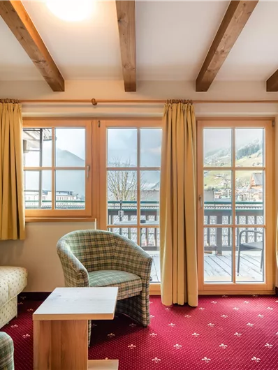 Ein gemütliches Zimmer mit Holzdecken und einem Balkon. Das Zimmer ist mit einem Sofa, einem Stuhl und einem Tisch ausgestattet.