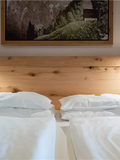 Ein gemütliches Schlafzimmer mit zwei getrennten Betten. An der Wand hängt ein Landschaftsbild, und sanfte Lampen sorgen für eine warme Atmosphäre.