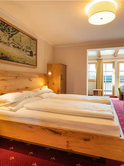 Ein gemütliches Schlafzimmer mit einem großen Bett und roten Teppich. Neben dem Bett stehen Nachttische und es gibt einen schönen Sitzbereich mit Fenster.