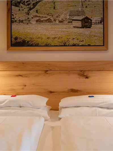 Ein gemütliches Schlafzimmer mit zwei Einzelbetten und warmem Holzdekor. Über dem Bett hängt ein Bild einer schönen Landschaft.