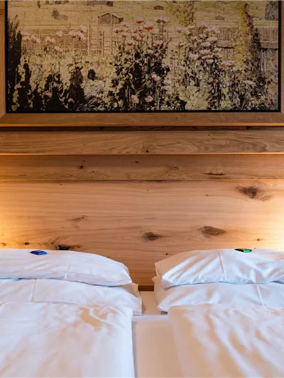 Ein gemütliches Schlafzimmer mit zwei Einzelbetten und warmem Holzdesign. An der Wand hängt ein künstlerisches Bild, das dem Raum Charakter verleiht.
