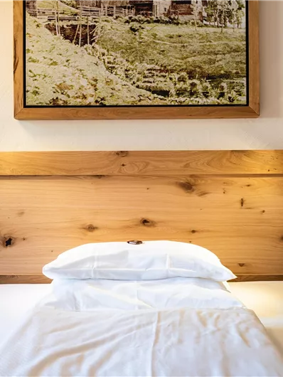 Ein gemütliches Schlafzimmer mit einem Holzbett und einer malerischen Wanddekoration. Die Nachttischlampen sorgen für eine angenehme Beleuchtung.