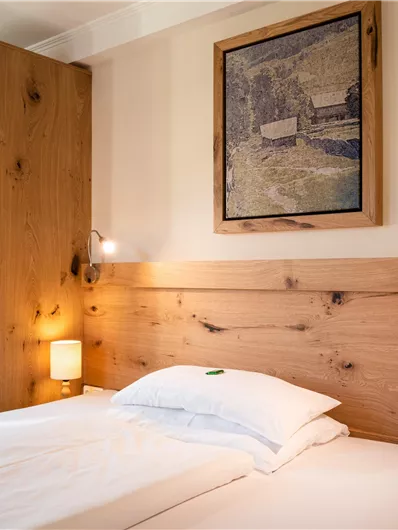 Ein modernes Schlafzimmer mit einem großen Bett und Holzregalen. Die Wände sind hell gestrichen, und es gibt sanfte Beleuchtung.