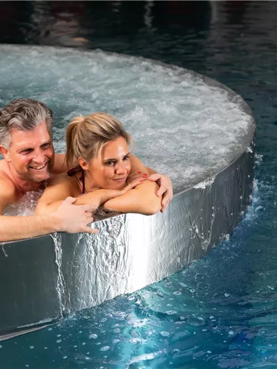 Een paar ontspant in een modern bubbelbad. Het water spuit om hen heen en creëert een prettige sfeer.